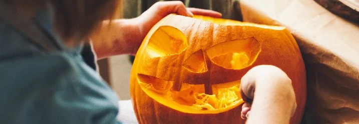 Person schnitzt Kürbis